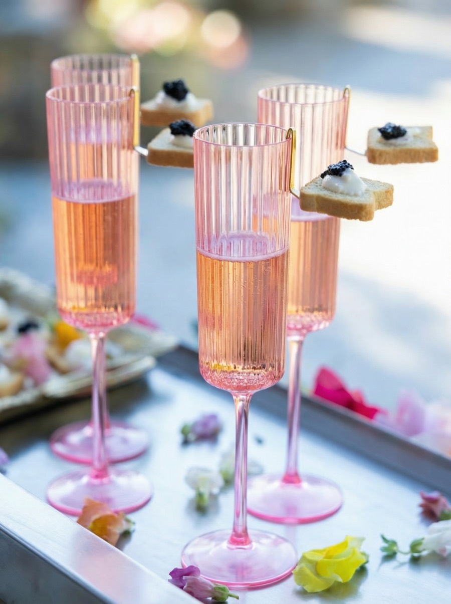 Rosé champagne in pink fluted glasses with caviar toasts clipped to the rim